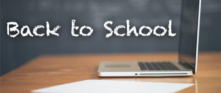 Back To School in white letters with an open laptop computer sitting on a desk