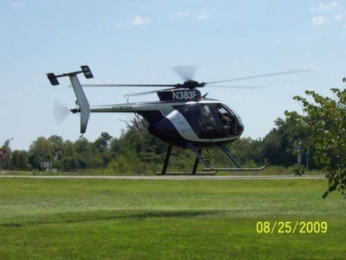 Helicopter N383F hovering above an open area of grass.